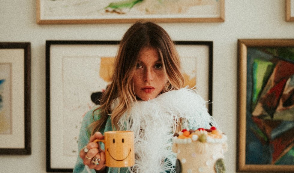 holding a smiley mug and a cake